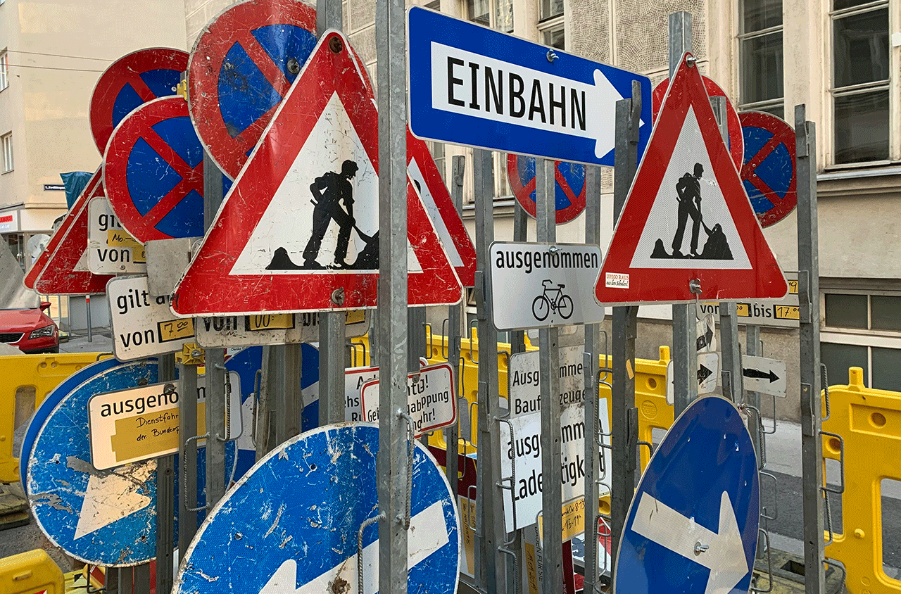 Overloaded street signage in Germany symbolising confusing, contradictory career advice for international professionals.